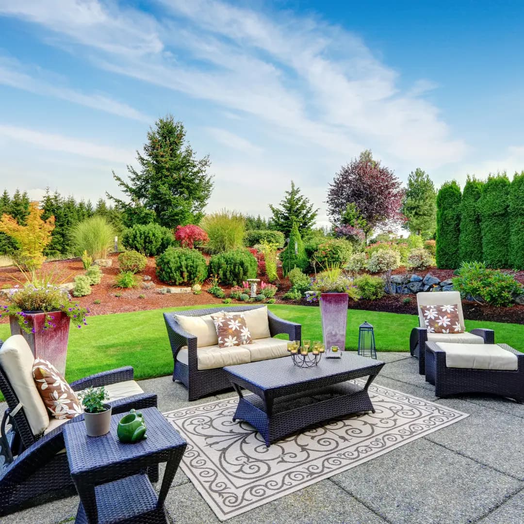 Layered planting beds and lawn framing a stone patio seating area