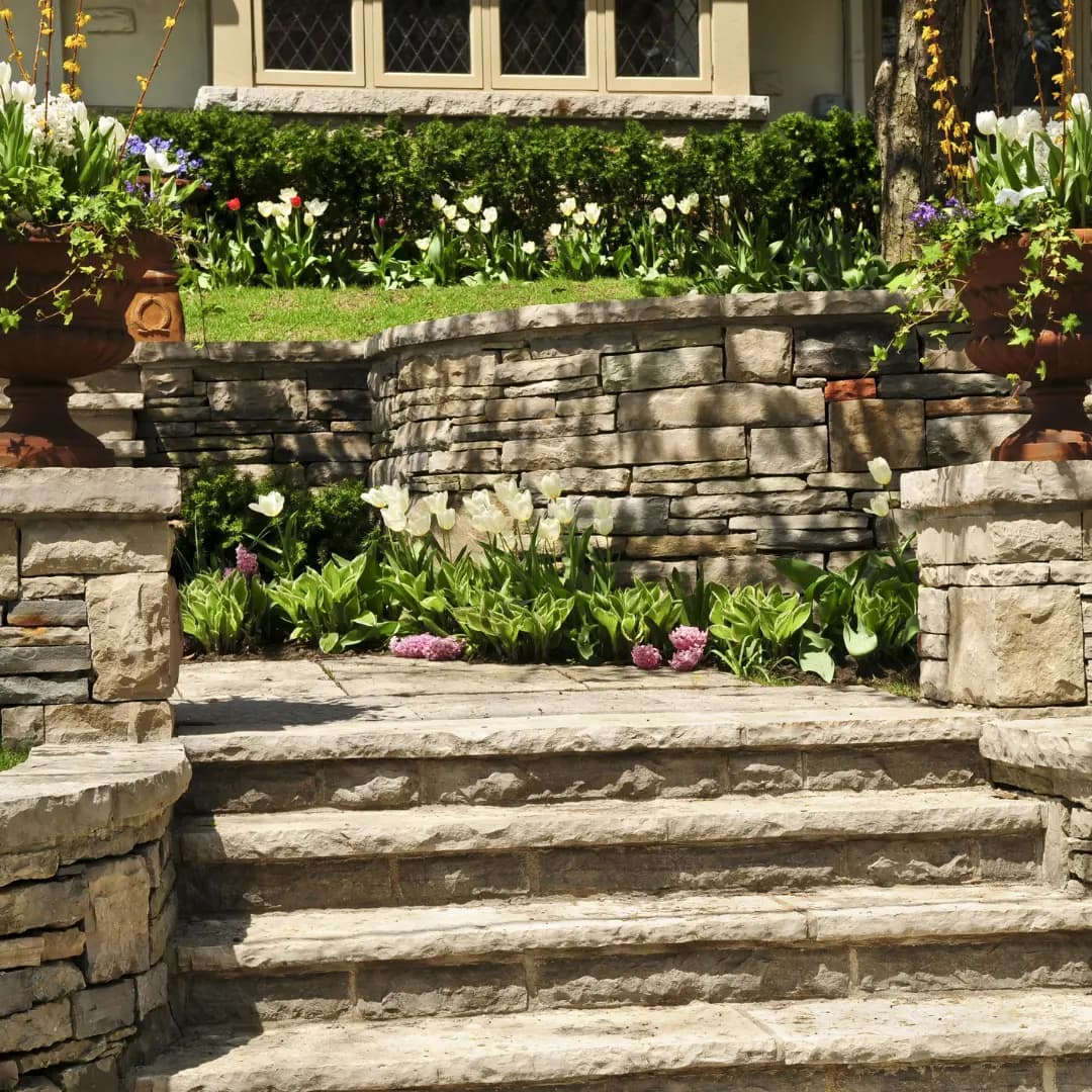 Stacked-stone retaining walls and steps terracing a planted slope